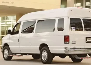Beli kombi parkiran ispred ulaza zgrade