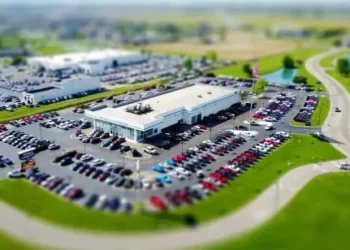 Ptičja perspektiva salona automobila sa velikim parkingom i mnogim parkiranim vozilima