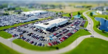 Ptičja perspektiva salona automobila sa velikim parkingom i mnogim parkiranim vozilima